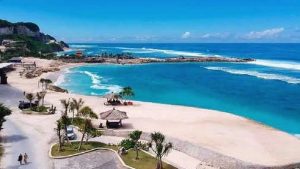 Pemandangan indah Pantai Melasti di Bali dengan pasir putih dan air laut biru jernih, dikelilingi tebing kapur yang megah.