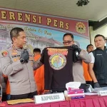 Kapolres Gianyar AKBP I Made Bayu Sutha Sartana menunjukkan barang bukti berupa kaos perguruan silat IKSPI Kera Sakti dalam konferensi pers kasus pengeroyokan yang melibatkan lima warga asal Kupang, Jumat (9/5/2025).