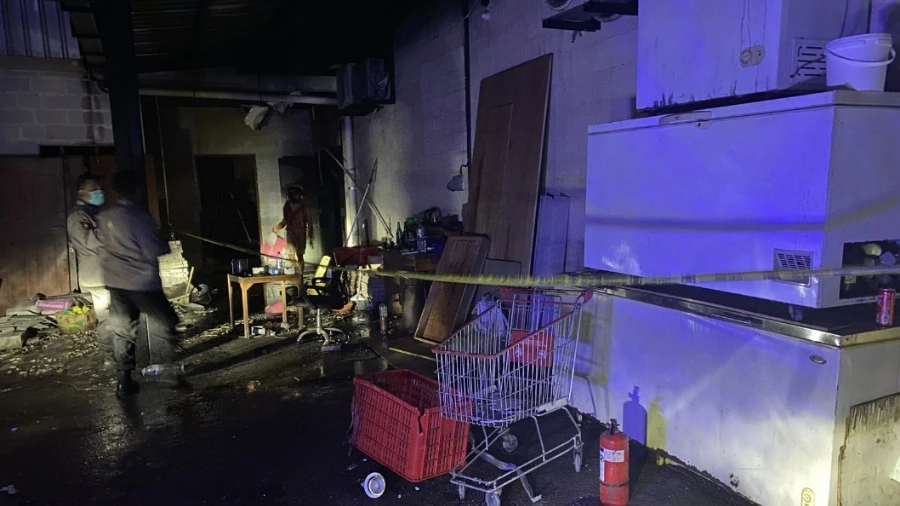 Petugas kepolisian memasang garis polisi di lokasi kebakaran gudang pengasapan daging di Jalan Sunset Road, Kuta, Bali, Kamis (22/5/2025) sore.