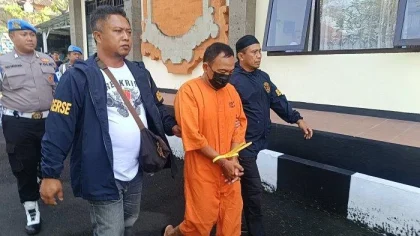 Petugas Satreskrim Polres Bangli menggiring Tjok Gede, seorang tersangka pencurian berseragam tahanan oranye usai rilis kasus di Mapolres Bangli, Senin (26/5/2025).