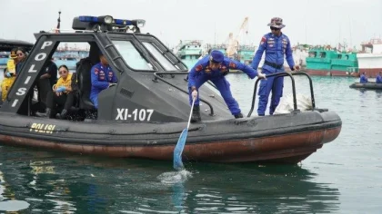 Anggota Ditpolairud Polda Bali memungut sampah plastik dari permukaan laut menggunakan jaring saat kegiatan bersih-bersih di perairan Pelabuhan Benoa dalam rangka memperingati Hari Bhayangkara ke-79. (Foto: Istimewa)