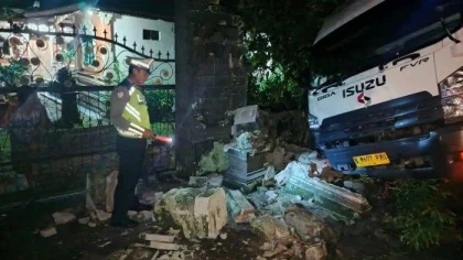 Seorang petugas kepolisian sedang memeriksa lokasi kecelakaan truk boks yang menabrak bangunan warga di jalur tengkorak Jalan Raya Denpasar–Gilimanuk, Desa Gumbrih, Kecamatan Pekutatan, Jembrana, Minggu dini hari, 8 Juni 2025. (Foto: Istimewa)