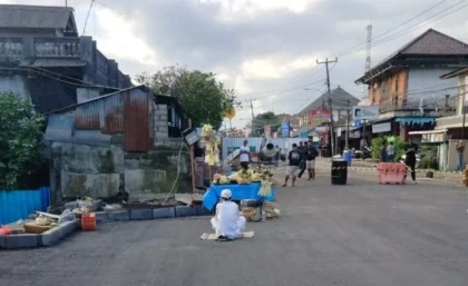 Seorang pemangku memimpin upacara Ngulap Ngambe di tengah ruas jalan nasional Denpasar–Gilimanuk yang baru selesai diperbaiki di depan Pasar Bajera, Kecamatan Selemadeg, Tabanan, Jumat (18/7/2025) pagi. (Foto: Istimewa)