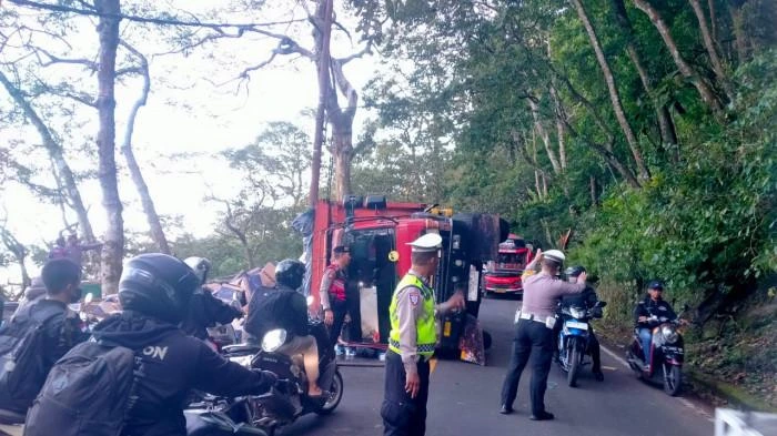 Petugas kepolisian mengatur arus lalu lintas saat sebuah truk pengangkut tisu terguling dan melintang di jalur menurun Desa Wanagiri, Kecamatan Sukasada, Buleleng, Kamis (17/7/2025). Peristiwa ini menyebabkan kemacetan selama dua jam di jalur alternatif Singaraja–Denpasar. (Foto: Istimewa)